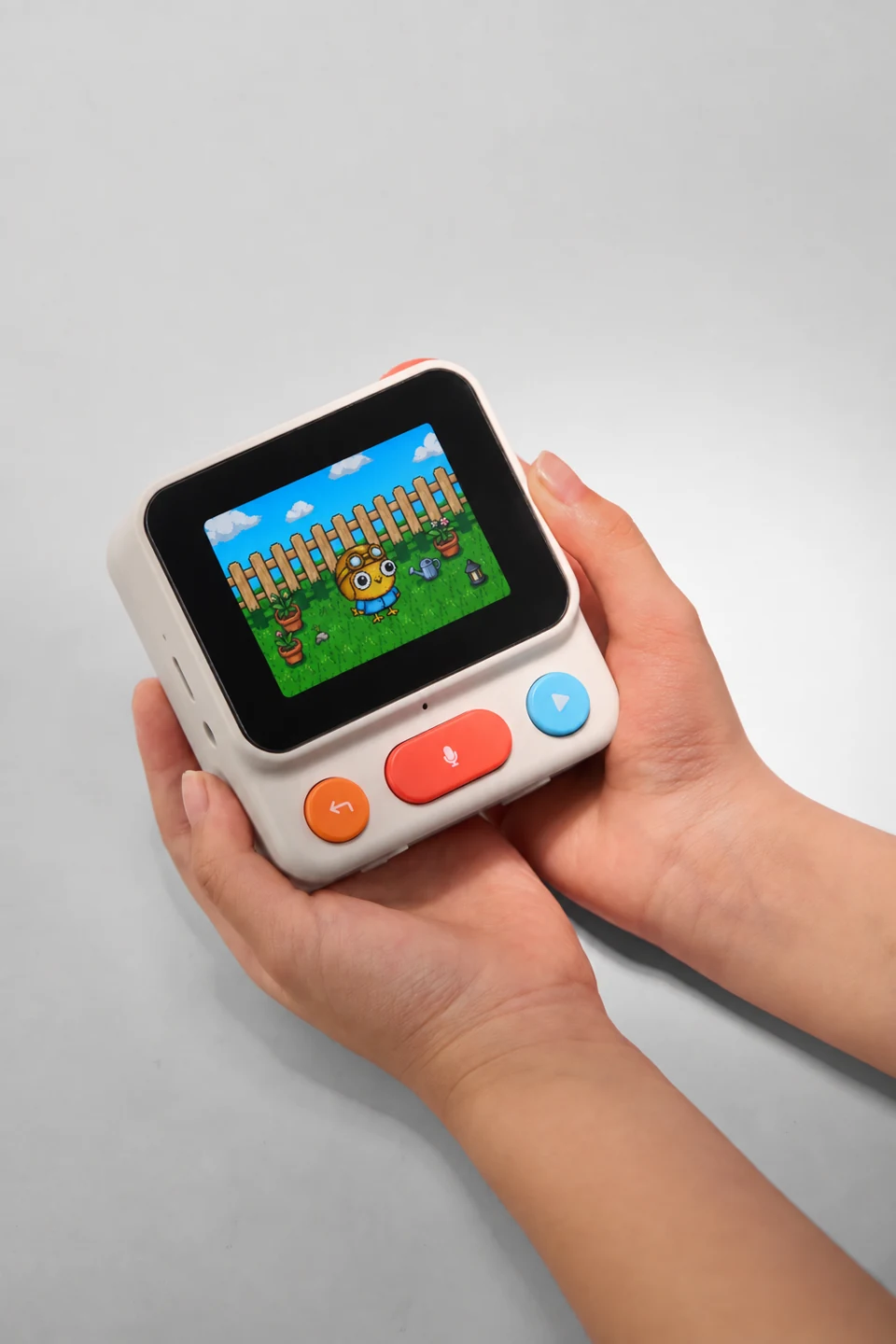 A hand holds the Nowa device, showing its screen and colorful buttons